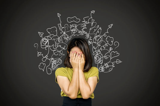 A young woman stands in front of a blackboard. Behind her are a lot of scribbles. 